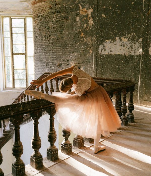 A serene woman in a bright room performing a gentle stretching movement.